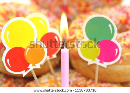 pink candle on colorful doughnut background