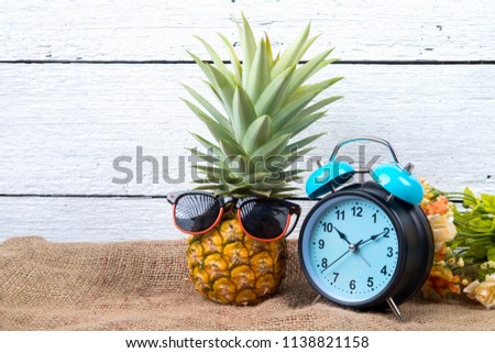 cute ripe pineapple with clock, sunglasses and headphone on sack and white wooden background.
