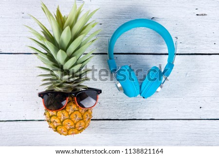 cute ripe pineapple with clock, sunglasses and headphone on sack and white wooden background.