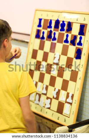 smart, cute, young boy is thinking about a move on the magnetic chessboard. Education concept, chess lesson, training,  intellectual game
