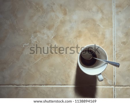 A cup of coffee on the floor.