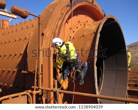 Closeup pictures of rope access  industrial inspector fitters, boilermaker wearing safety harness using twin rope abseiling inspection chute at construction mining site Perth, Australia