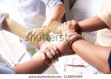 5 people hold hands together represent cooperation in a teamwork in the light leading to a success of the organization Royalty-Free Stock Photo #1138993499