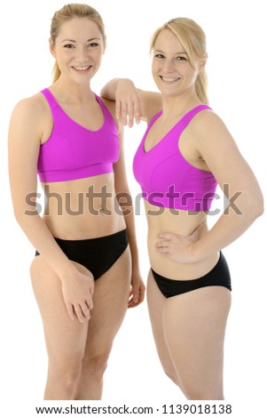 Two beautiful sporty young blond women in sports wear posing in studio isolated on white