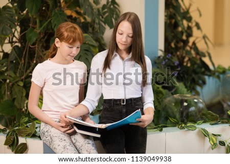 student girls are sitting at a Desk and learn in school, free University