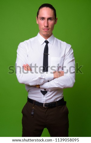 Young handsome businessman against green background
