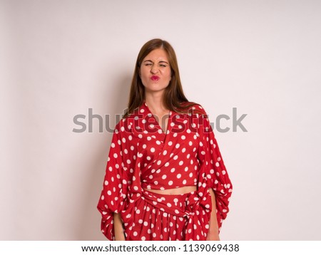 beautiful young woman with long hair in red skirt and top in modeling photoshoot captured in photo studio against light backdrop
