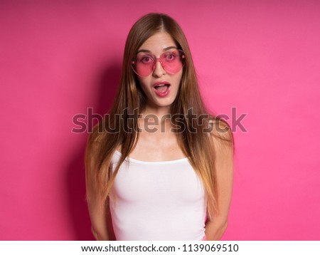 Beautiful young woman with long hair in white shirt in modeling photoshoot captured in photo studio with light red backdrop