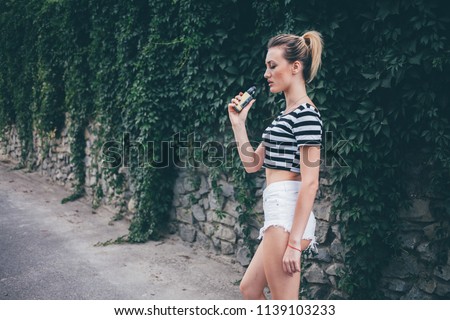 beautiful young woman with big red lips smokes electronic cigarette