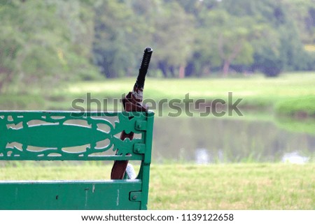An umbrella on the white bench at the park with green nature background and blurred a water view