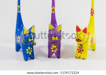 Perspective front shot of blue, yellow and purple cat figures of wooden carved nicknack