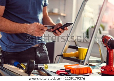 Men renovating kitchen and shopping construction material online on smart phone