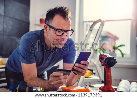 Men shopping construction material online during kitchen renovation on smart phone