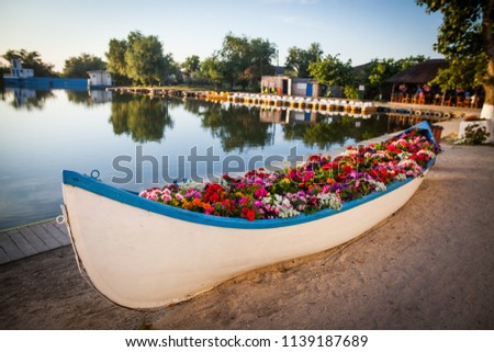 Color image of a wooden boat filled with various flowers.