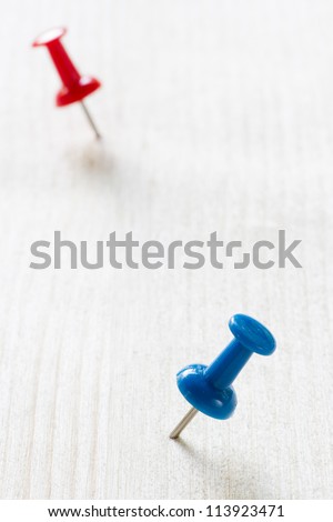 Macro of Blue and red push pins on the wood plane