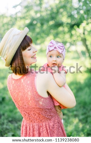 Beautiful Mother with the straw hat And her little daughter outdoors family look in in a pink dress . Outdoor Portrait of happy family. family look. Mother and her daughter in summer park.