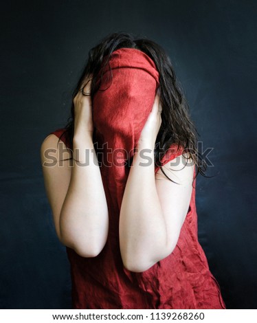 photo of a girl hides her face in a red drapery wet hair