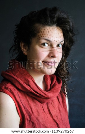 photo portrait of playful girl with ethnic patterns on face in red clothes wet dark hair