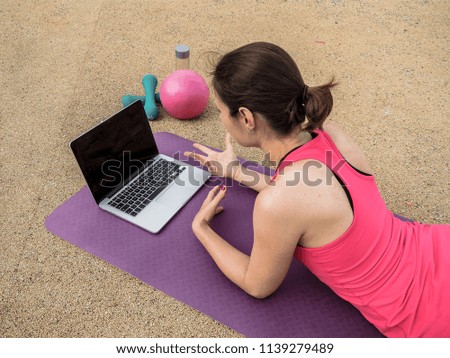 fitness coach explaining online fitness program infront of a laptop on a mat from top view
