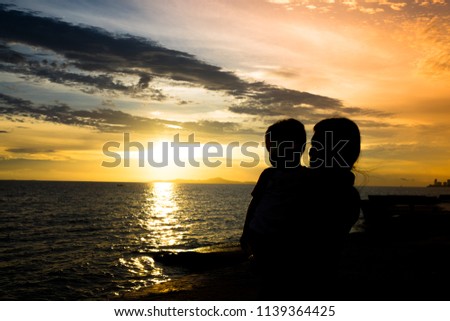 Silhouette of a Little Baby boy with his Mother on the beach at the sunset time. family concept. Copy Space. Background.