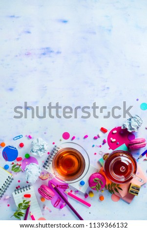 Tea party with a tiny glass teapot, candies, and confetti on a light background with copy space. Pink and purple palette still life. Vibrant drinks concept