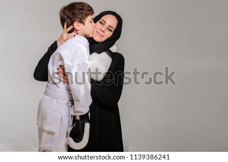Happy Muslim mom with little son in kimono hugging after competition.