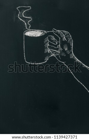 Chalk hand drawing a hand holding coffee cup with steam on black board near top of the frame.