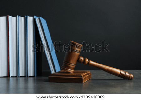 Wooden gavel and books on table against dark background. Law concept