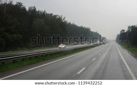 Countryside road and several cars in rainy overcast day