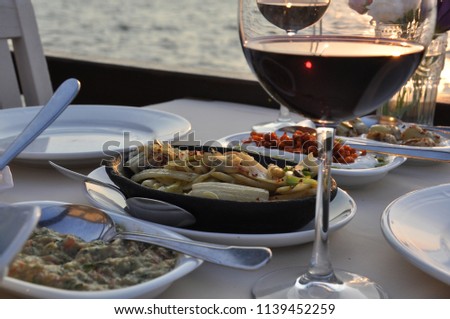 Romantic dinner. Wine at sunset. For Valentine's Day. For a marriage proposal. Octopus, shrimp, calamari, grilled fish, red wine, wonderful restaurant on the seaside.