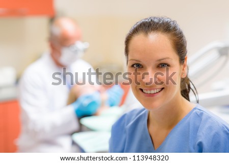 Female dental assistant smiling at stomatology office dentist with patient Royalty-Free Stock Photo #113948320