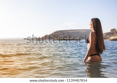 Young woman standing in the sea on summer.