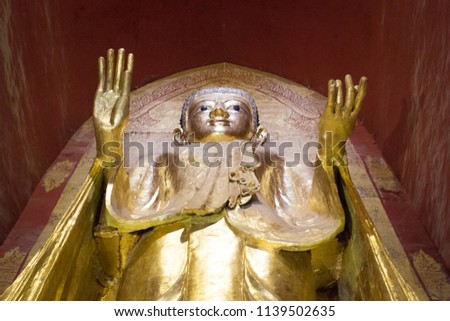 A standing Bhddha statue in gold color from below