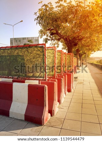 Red and white concrete barrier. Beautiful sunset sky and trees background.