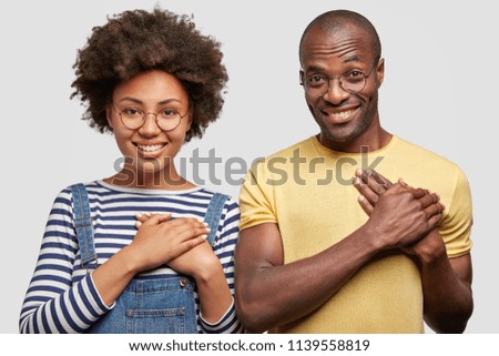 People, ethnicity and gratitude concept. Smiling young African American female and male keep hands on chest, have friendly expressions, isolated over white background, feel thankful to somebody Royalty-Free Stock Photo #1139558819