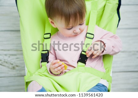 Concept control and care for the child and his safety. The child is fastened to a chair, active children, a seat belt. The interest of the kid in limiting his freedom