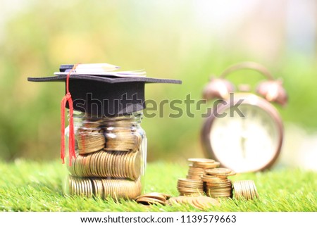 Graduation hat on the glass bottle with Stack of gold coins money on natural green background, Saving money for education concept