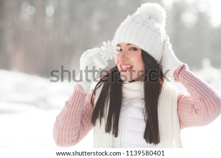 Portrait of young cheerful woman with snowflake in winter background