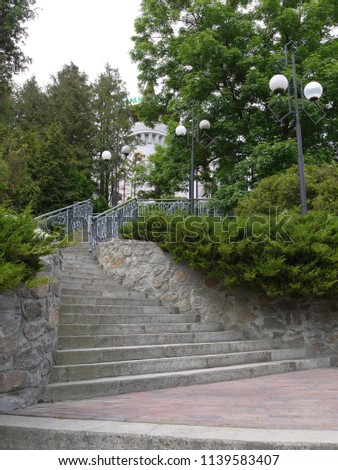 A staircase with tapering upstairs steps with side lamps for lighting at night leading up to the hotel building.