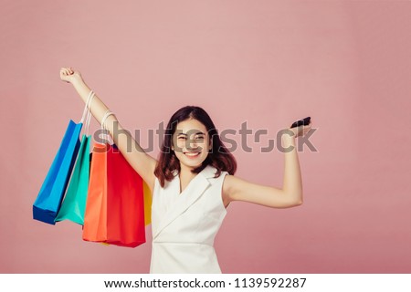 Women holding shopping bags looking up to the side on pink background at copy space.she is using smart phone shoping online ,ecommerce. Royalty-Free Stock Photo #1139592287