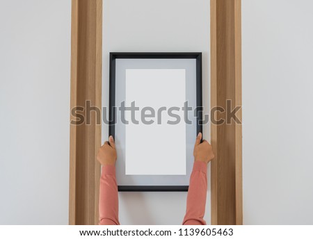 Female hands hold a blank photo frame.