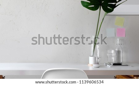 Workspace and copy space with monstera on white desk.