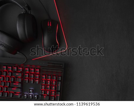 gamer workspace concept, top view a gaming gear, mouse, keyboard, joystick and mouse pad on black table background with copy space.