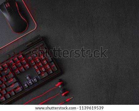 gamer workspace concept, top view a gaming gear, mouse, keyboard, joystick and mouse pad on black table background with copy space.