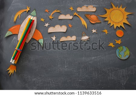 Back to school concept. rocket, space elements shapes cut from paper and painted over class room blackboard background