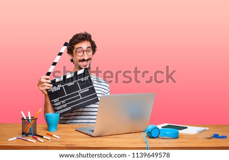 young crazy graphic designer on a desk with a laptop and with a cinema clapper