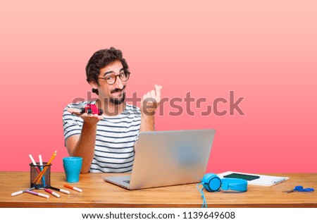 young crazy graphic designer on a desk with a laptop and with a red car model
