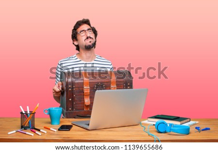 young crazy graphic designer on a desk with a laptop and with a pirate chest
