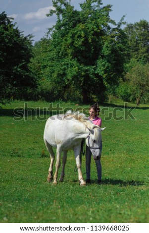 rider young woman in jeans rides a horse against a background of green trees
