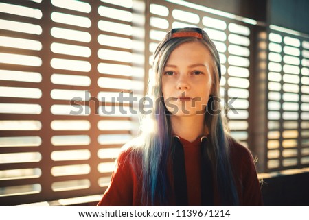 Portrait of young stylish hipster girl with pink hair at sunset